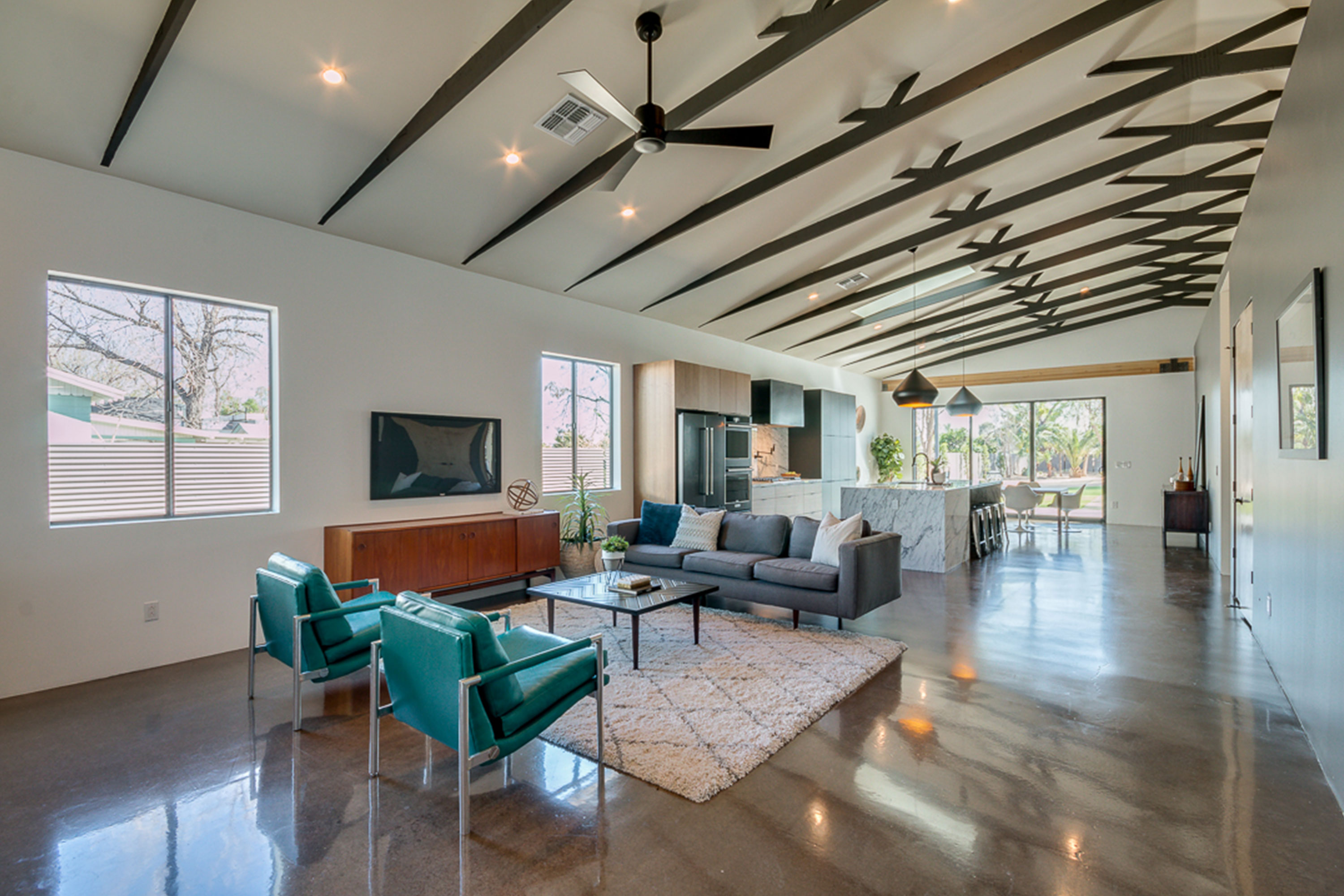 Modern open concept livingroom & kitchen with 20ft ceiling at center of vault, exposed structural scissor trusses